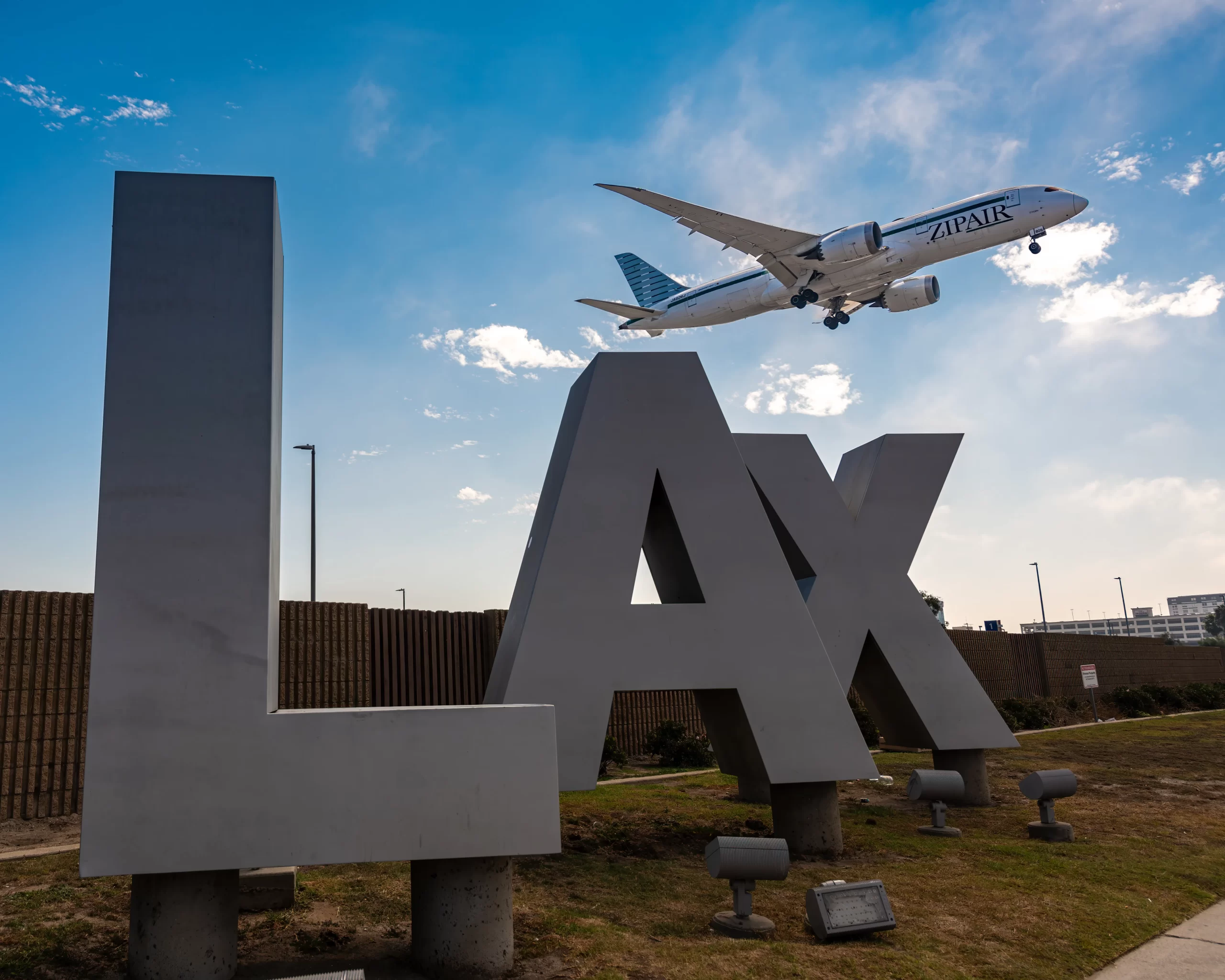 Plane taking off above LAX sign